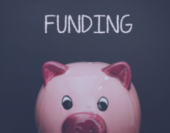 Piggy bank with funding written on blackboard in background.