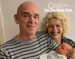 Person living with lung cancer hold baby with partner stood next to them.